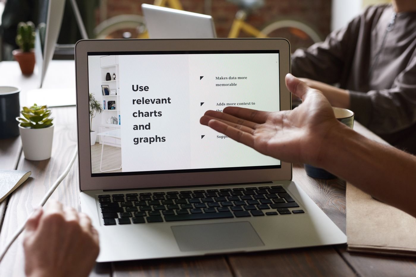 A person pointing at a laptop screen while explaining something