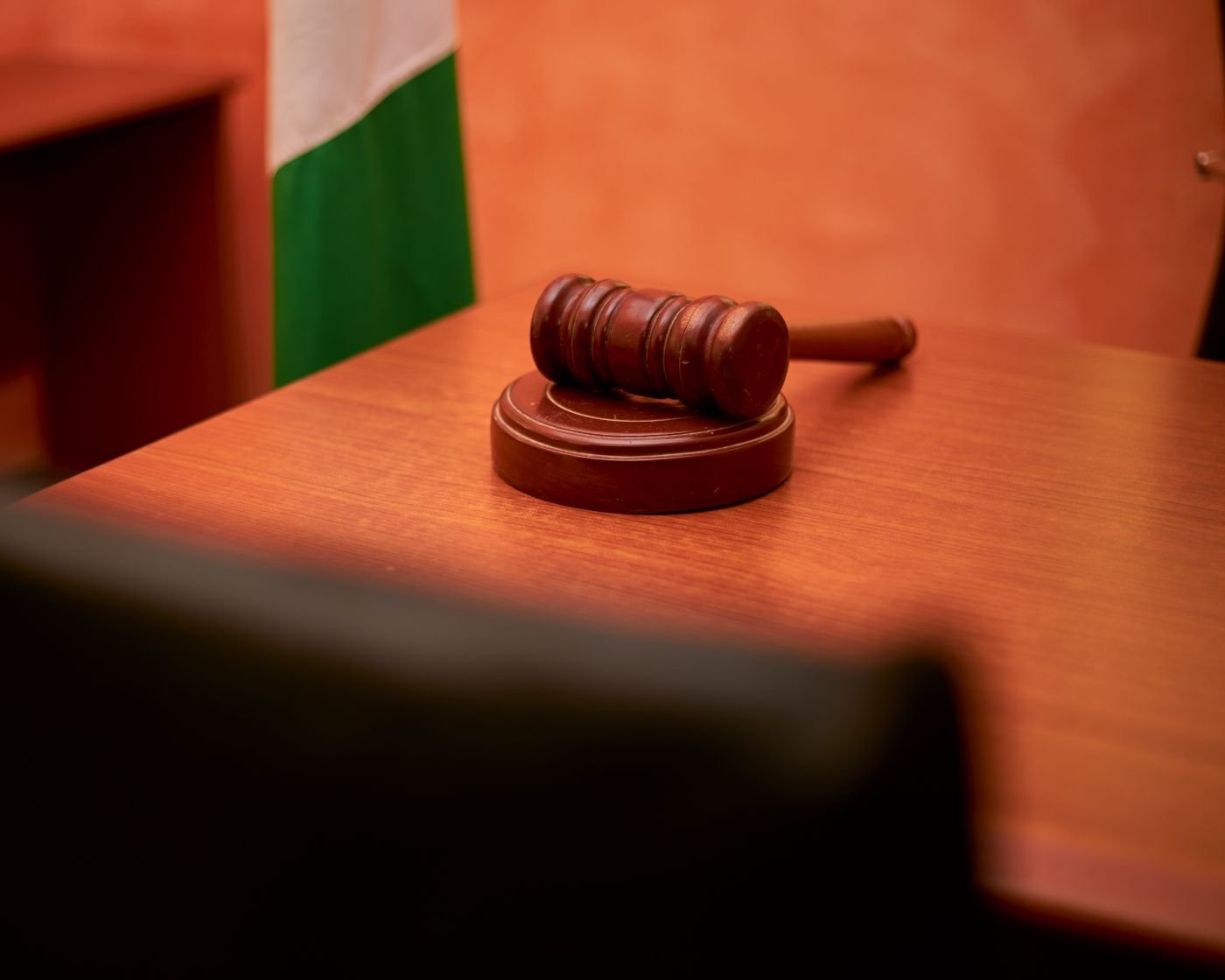 A gavel and justice scales on a wooden surface, representing a regulatory fine