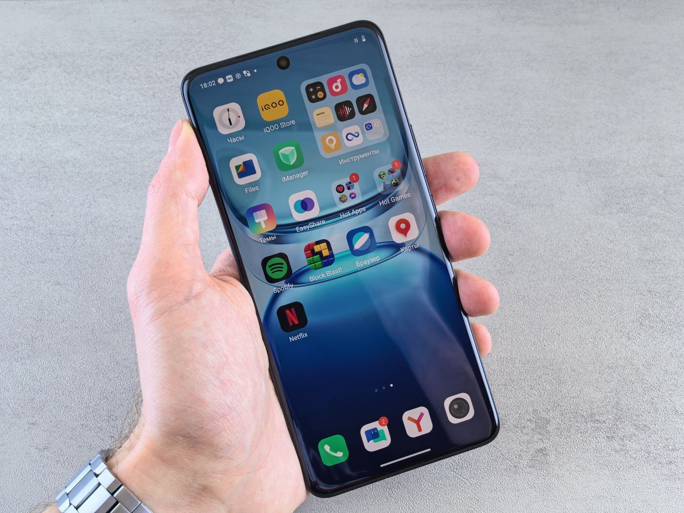 Hand holding a smartphone showing managed app icons on the home screen