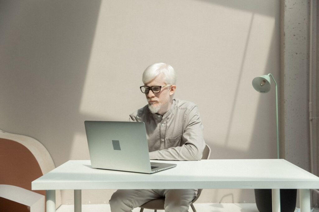 An IT administrator working at a laptop in a bright office, reviewing a hybrid identity sync configuration